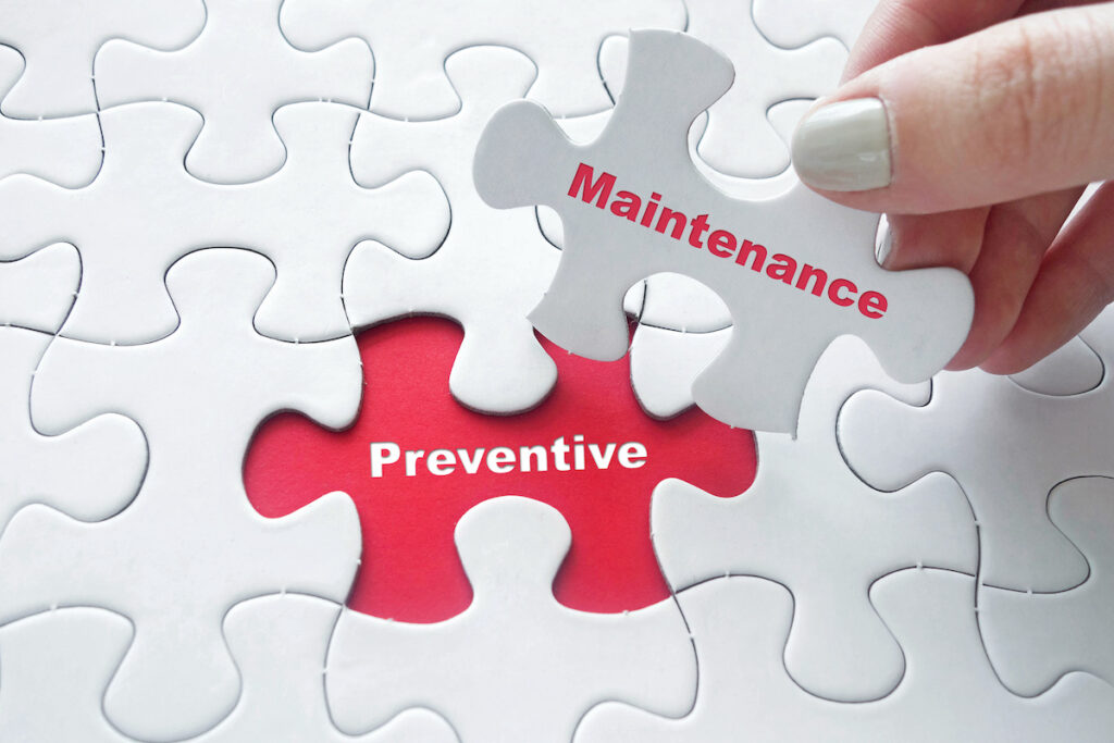 Close up of girl's hand placing the last jigsaw puzzle piece with word Preventive Maintenance